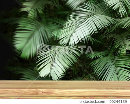 Old wooden table and palm leaves. Empty wooden table top and green tropical plant leaf on black background Old wooden table and palm leaves. Empty wooden table top and green tropical plant leaf on black background 90244189