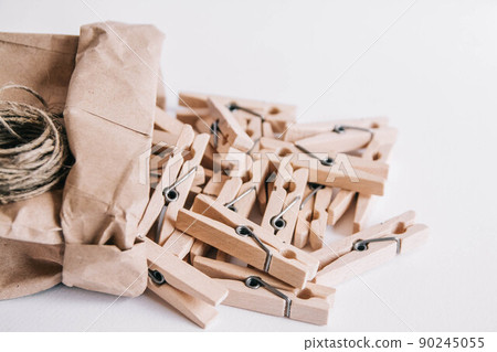 Wooden clothespins in paper bag with rope on white background. View from above. Place for your text 90245055