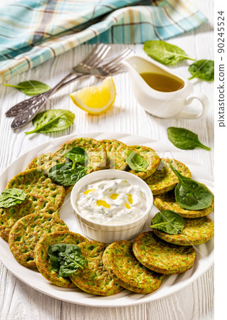 spinach pancakes on white plate with sauce 90245524