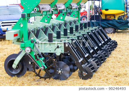 A fragment of a multi-row seeder with knife harrows for field work against the background of yellow stubble. 90246493