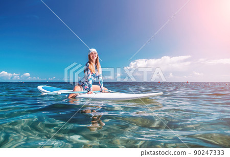 Healthy happy fit woman in bikini relaxing on a sup surfboard, floating on the clear turquoise sea water. Recreational Sports. Stand Up Paddle boarding. Summer fun, holidays travel. Active lifestyle 90247333