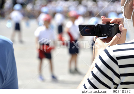 Dad shoots a child's athletic meet with a video camera 90248182