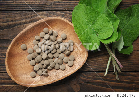 Burdock leaves and pills with extract of arctium lappa. Top view. Burdock leaves and pills with extract of arctium lappa. Top view. 90249473