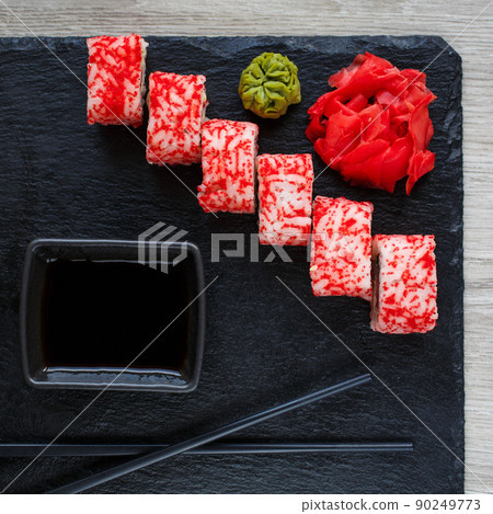 Sushi roll with seafood and soy sauce, wasabi and ginger. Sushi roll with caviar on a black board. Sushi roll with seafood and soy sauce, wasabi and ginger. Sushi roll with caviar on a black board. 90249773