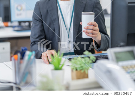 SDGs Up the hands of a young businessman drinking a drink in a tumbler in the office SDGs Up the hands of a young businessman drinking a drink in a tumbler in the office 90250497