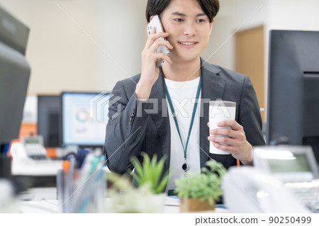 Young businessman drinking a tumbler in the SDGs office Young businessman drinking a tumbler in the SDGs office 90250499