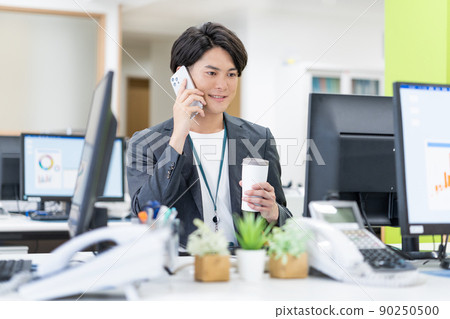 Young businessman drinking a tumbler in the SDGs office 90250500
