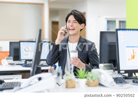 Young businessman drinking a tumbler in the SDGs office Young businessman drinking a tumbler in the SDGs office 90250502