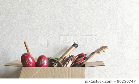 Lots of old musical instruments and toys in cardboard boxes_white wall background 90250747