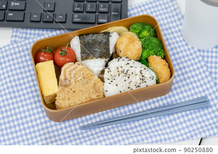 Rice ball lunch box and my chopsticks placed in front of the computer 90250880