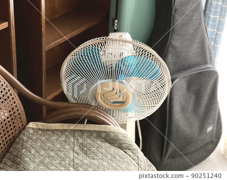 A fan and a wisteria chair in the corner of the room 90251240