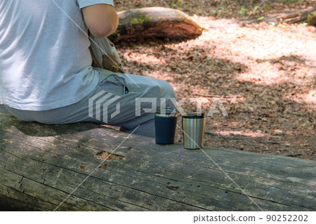 Traveler food for outdoor activities. Two metal thermo cups on a forest background. Enjoy a coffee during trips. Traveler food for outdoor activities. Two metal thermo cups on a forest background. Enjoy a coffee during trips. 90252202