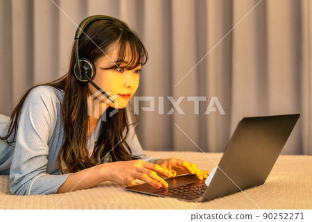 一名年輕女子在午夜用耳機檢查她的電腦 90252271
