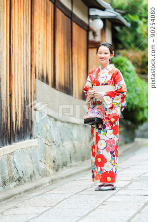 A young woman in a kimono walking on the cobblestones of Kyoto 90254080
