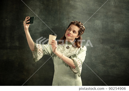 Emotional young beautiful girl, actress in image of medieval person posing isolated on dark background. Comparison of eras concept, flemish style. Art, beauty 90254906