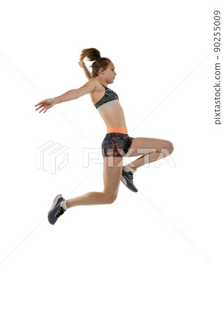 Long jump technique. Studio shot of professional female athlete in sports uniform jumping isolated on white background. Concept of sport, action, motion, speed. 90255009