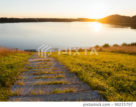 Beautiful sunset over Kenozero lake. Landscape with smooth water surface and wooden steps. Hiking in Karelia, Russia. Beautiful sunset over Kenozero lake. Landscape with smooth water surface and wooden steps. Hiking in Karelia, Russia. 90255797