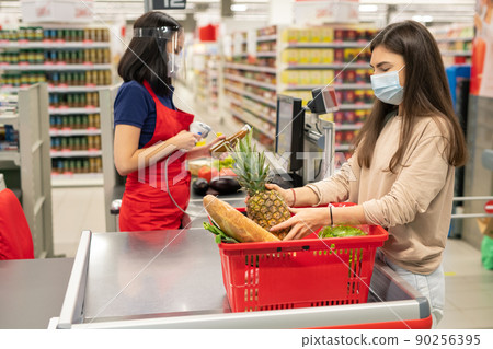Supermarket cashier and customer following personal protection rules during coronavirus quarantine days, wearing masks Supermarket cashier and customer following personal protection rules during coronavirus quarantine days, wearing masks 90256395
