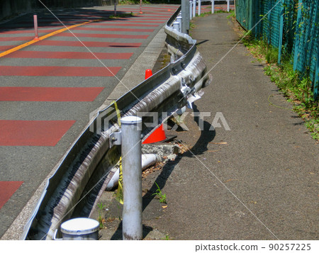 A guardrail that bends sharply on the sidewalk side of the road 90257225