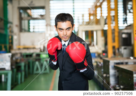 Asian businessman with boxing gloves in factory ready to fight Asian businessman with boxing gloves in factory ready to fight 90257506