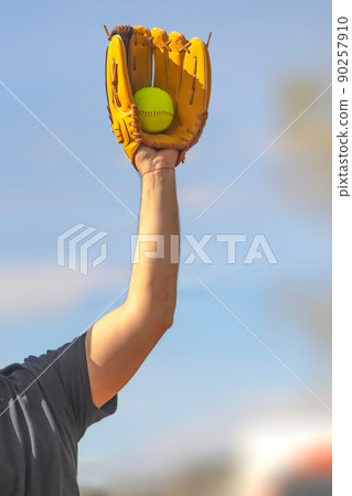 A Vertical view of a baseball player holding a glove and a ball.  90257910