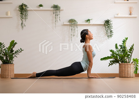 Side view of Asian woman wearing green sportwear doing Yoga exercise,Yoga Child pose or Balasana,Calm of healthy young woman breathing meditation with yoga at home,Exercise for wellness life 90258408