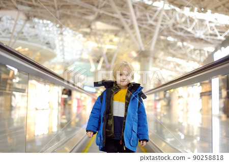 Little traveler on a high-speed sidewalk at an international airport. Family trip for winter holidays. Kids vacations. Little traveler on a high-speed sidewalk at an international airport. Family trip for winter holidays. Kids vacations. 90258818