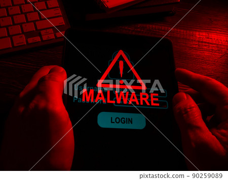 Hands in the dark hold a tablet with an inscription malware. 90259089