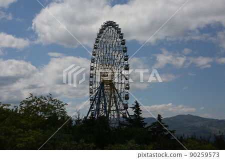 Ferris wheel. Amusement park with a big wheel for an overview of the city. Steel metal structure with cabins for people Ferris wheel. Amusement park with a big wheel for an overview of the city. Steel metal structure with cabins for people 90259573