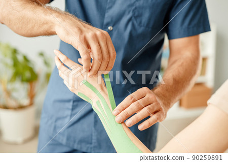 Therapist Putting Physio Tape on Hand 90259891