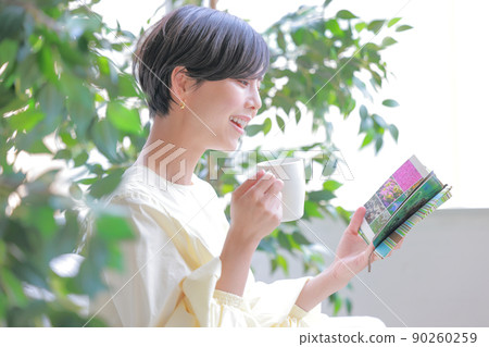 一個微笑的女人，一隻手拿著杯子看書 3 90260259