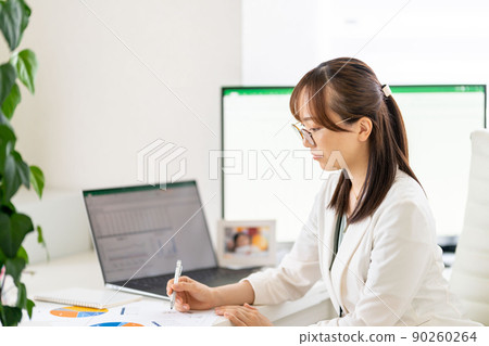 Young female engineer working from home, paperwork graph, glasses 90260264