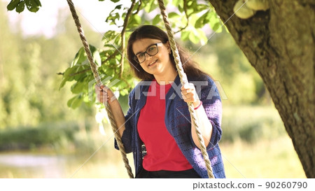 Young beautiful long-haired girl on a rope swing. 90260790