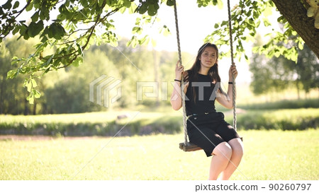 Young beautiful long-haired girl on a rope swing. 90260797