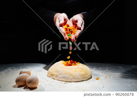 women's hands knead dough with candied fruits for easter cakes. black background 90260878