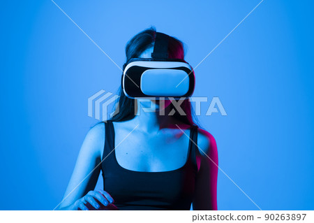 Smile happy woman getting experience using vr-headset glasses of virtual reality much gesticulating hands on gray background. Girl spend shes time in metaverse. 90263897