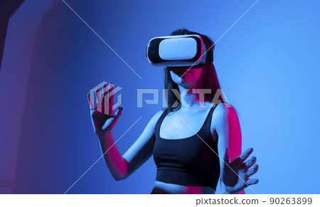 Young woman working in VR goggles on a grey background. Modern architect using virtual reality glasses at workplace. Designer working in augmented reality vr studio. 90263899