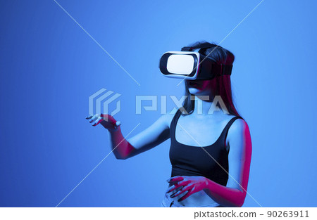 Young woman working in VR goggles on a grey background. Modern architect using virtual reality glasses at workplace. Designer working in augmented reality vr studio. 90263911