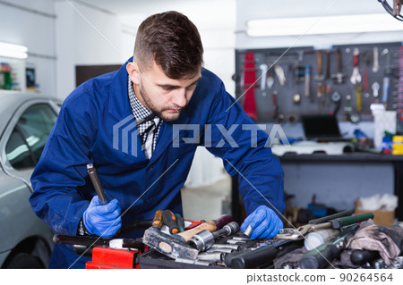 Man master is choosing instruments for work in workshop. 90264564