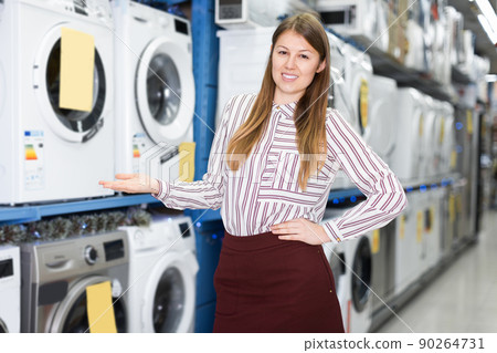 Polite salesgirl suggesting modern washer in store Polite salesgirl suggesting modern washer in store 90264731