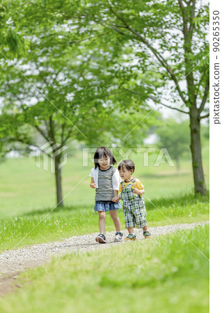 My older sister and brother playing in a fresh green park 90265350