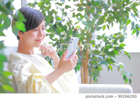 一個面帶微笑的女人看著她的智能手機 1 90266200