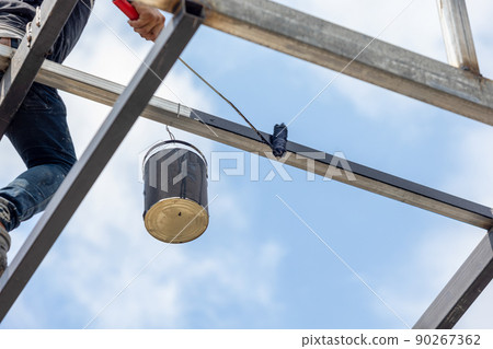Unsafe construction of workers while painting steel pipe of high rise building. 90267362