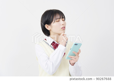 High school girl worried about holding a smartphone on a white background High school girl worried about holding a smartphone on a white background 90267688