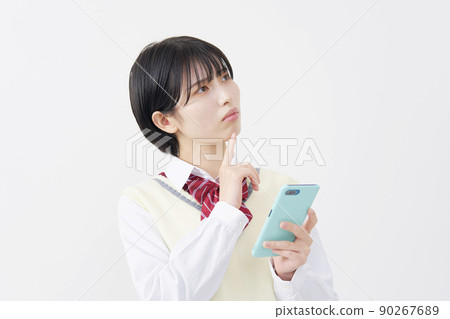 High school girl thinking with a smartphone on a white background 90267689