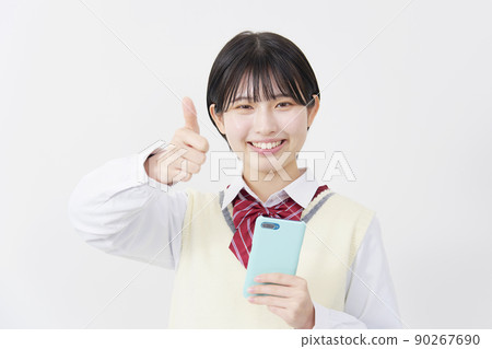 High school girl holding a smartphone on a white background and signing good High school girl holding a smartphone on a white background and signing good 90267690
