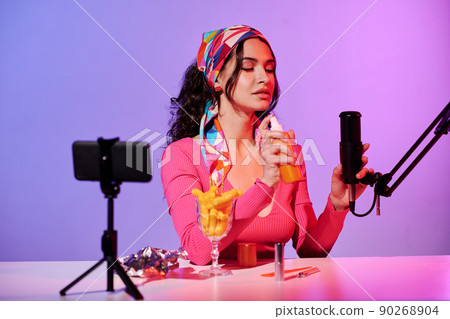 Young woman wearing fashionable outfit sitting in studio recording ASMR sound of spraying something Young woman wearing fashionable outfit sitting in studio recording ASMR sound of spraying something 90268904