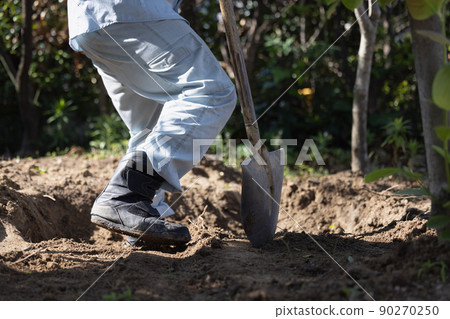 A man working to fill a hole in the garden A man working to fill a hole in the garden 90270250