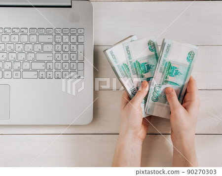 Hands holding russian rubles near laptop 90270303