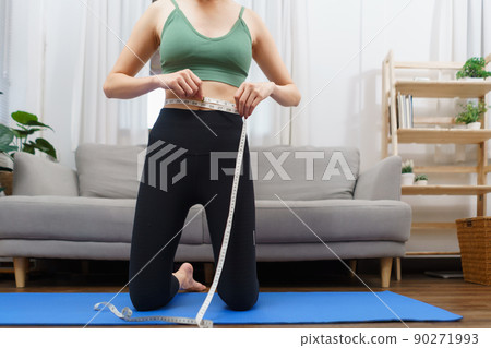 Healthy and weight loss concept, Young Asian woman is measuring her waist with tape measure Healthy and weight loss concept, Young Asian woman is measuring her waist with tape measure 90271993
